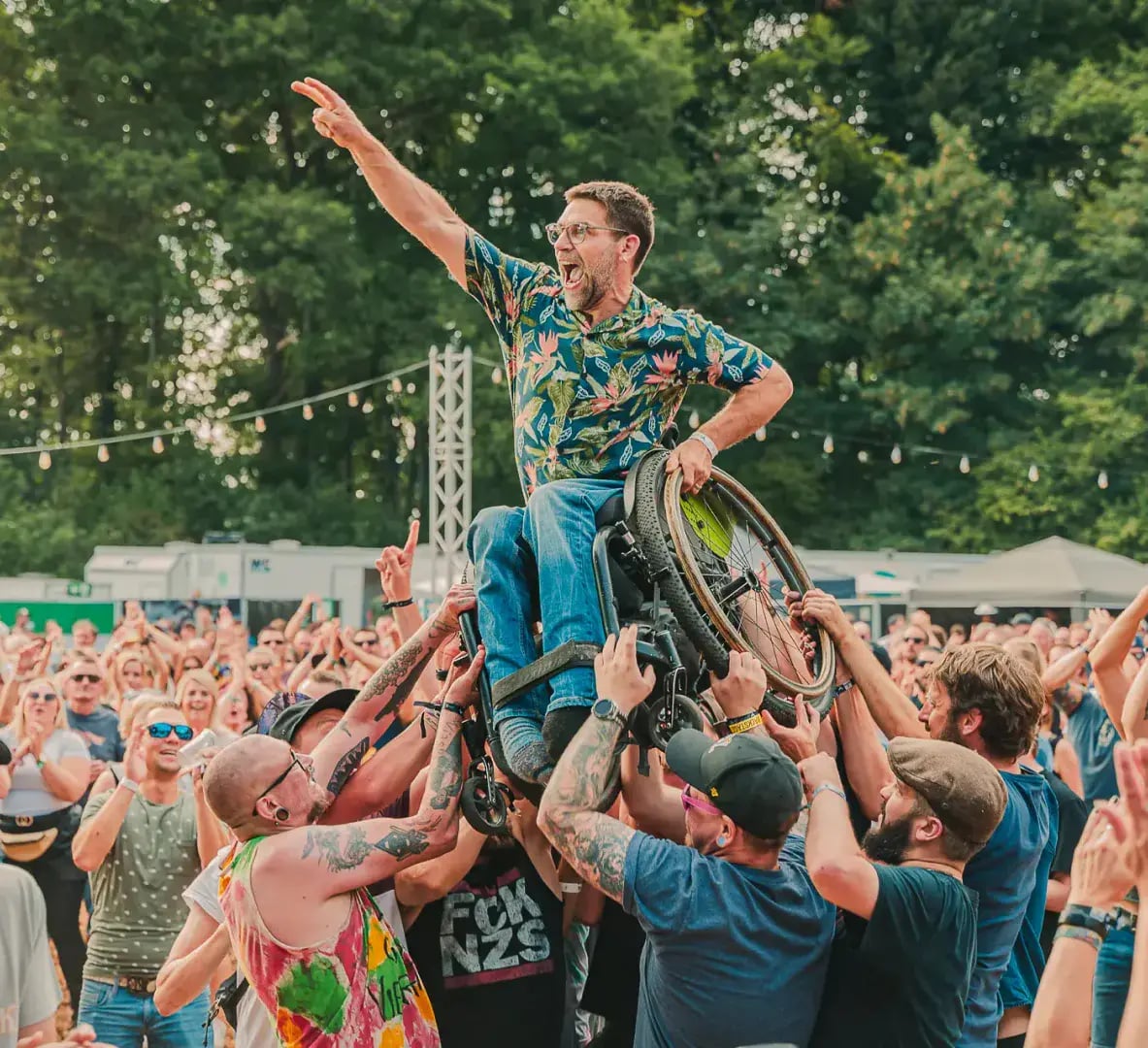 Besucher im Rollstuhl wird beim Da ist was im Busch Festival vom Publikum getragen