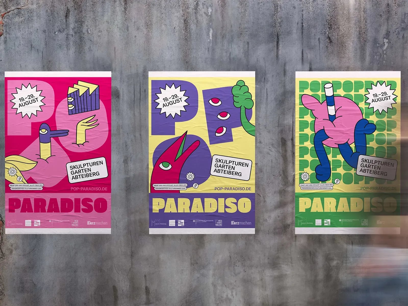 Bunte Festivalplakate von Pop Paradiso mit Illustrationen von Sebastian Jung an einer Betonwand.